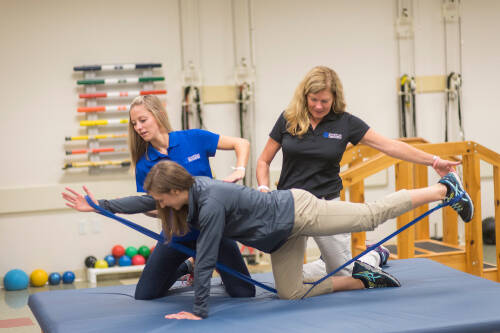 three students practice a physical therapy exercise